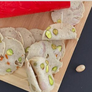Sliced lyoner mortadella with pistachios on a cutting board