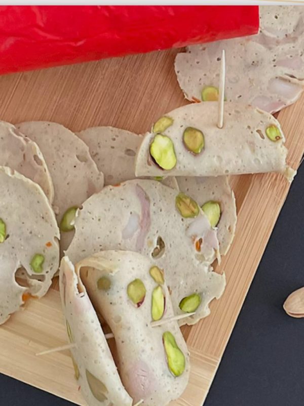 Sliced lyoner mortadella with pistachios on a cutting board